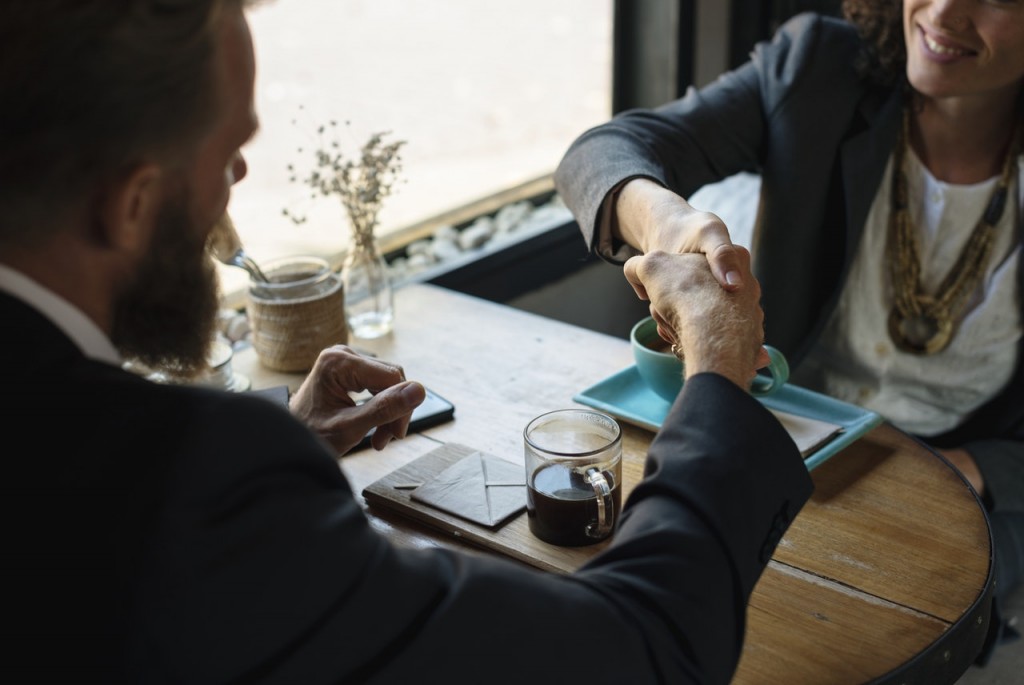 Man and woman shaking hands at a table