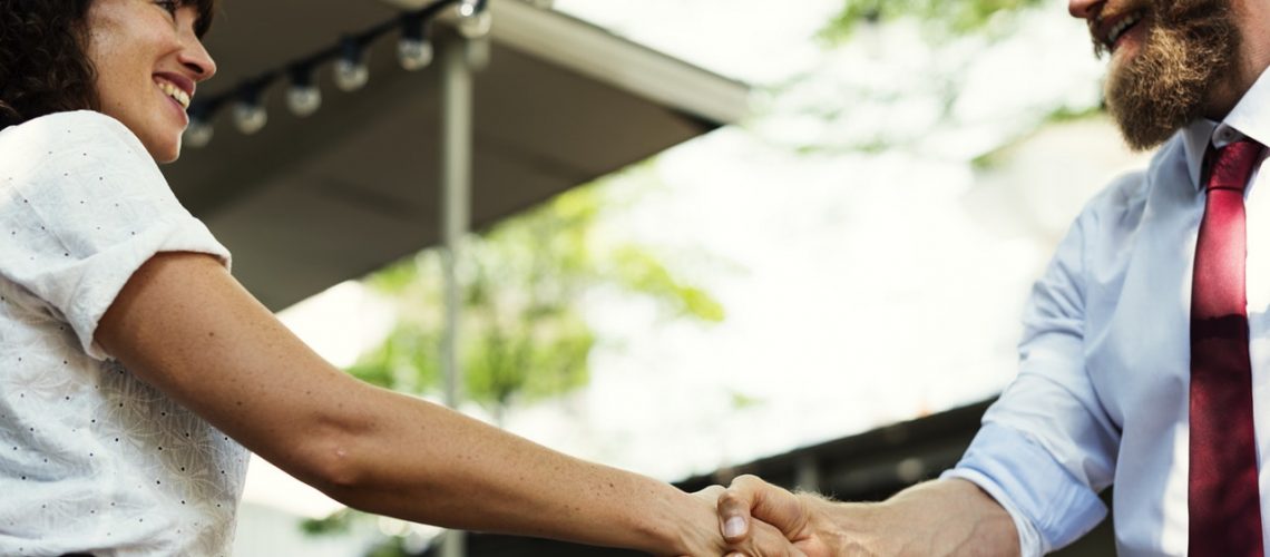 woman and man shaking hands smiling